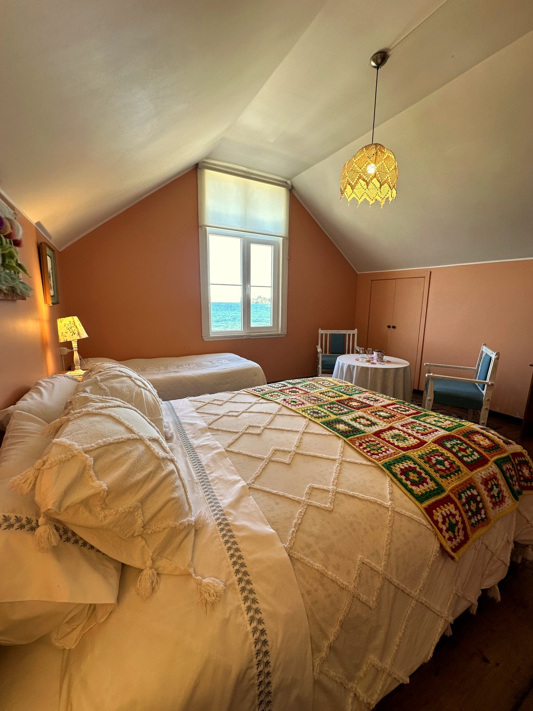 Habitación 8: cama matrimonial y cama adicional en tonos terracota, con rincón de estar y vista al lago
