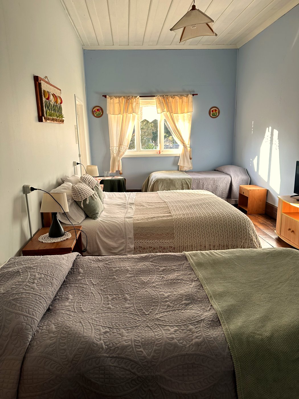 Habitación 9: cama matrimonial y dos camas adicionales en tonos celestes, con clóset y TV